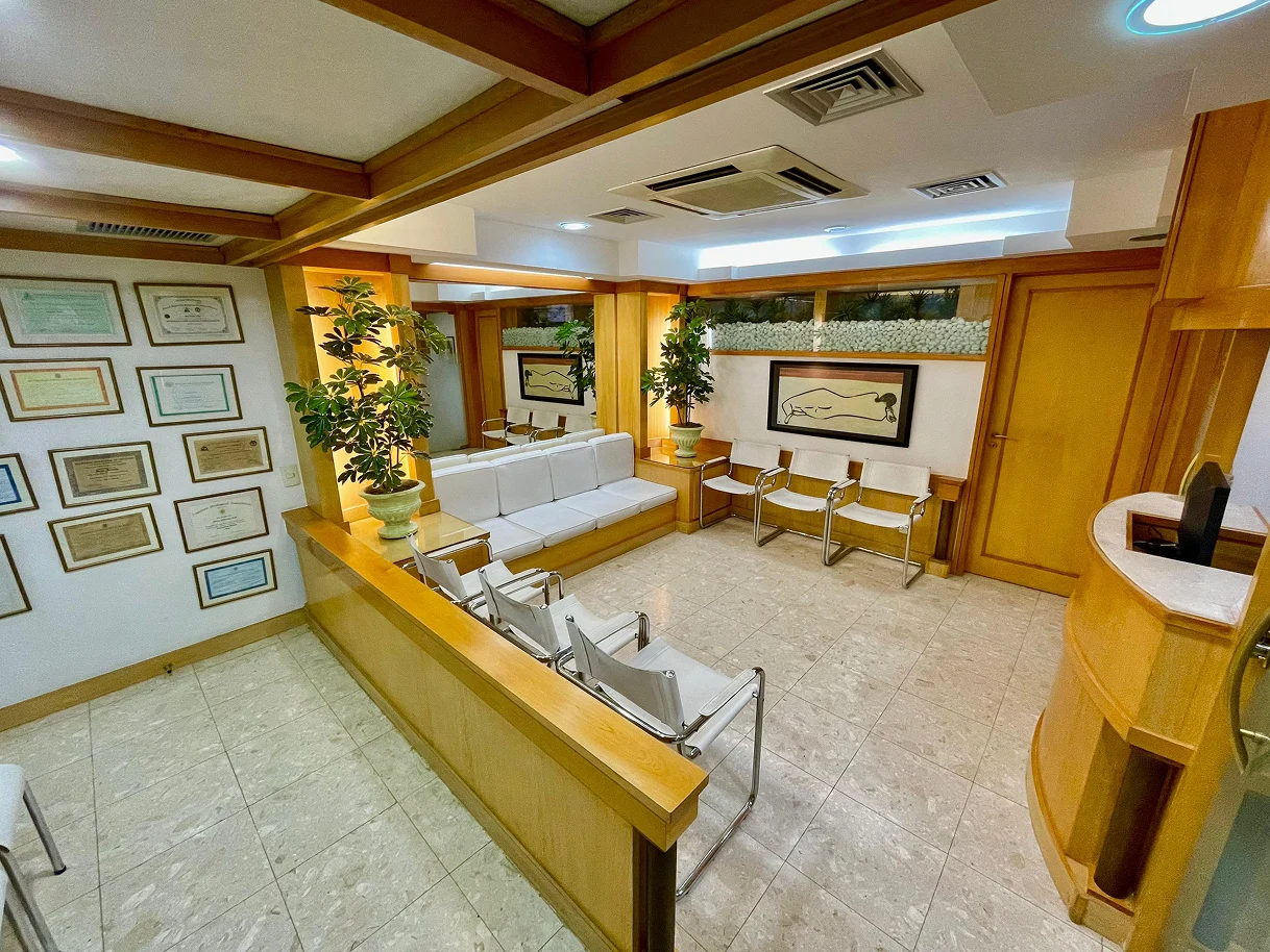 Sala de espera com parede de diplomas e certificações do Dr. Henrique
